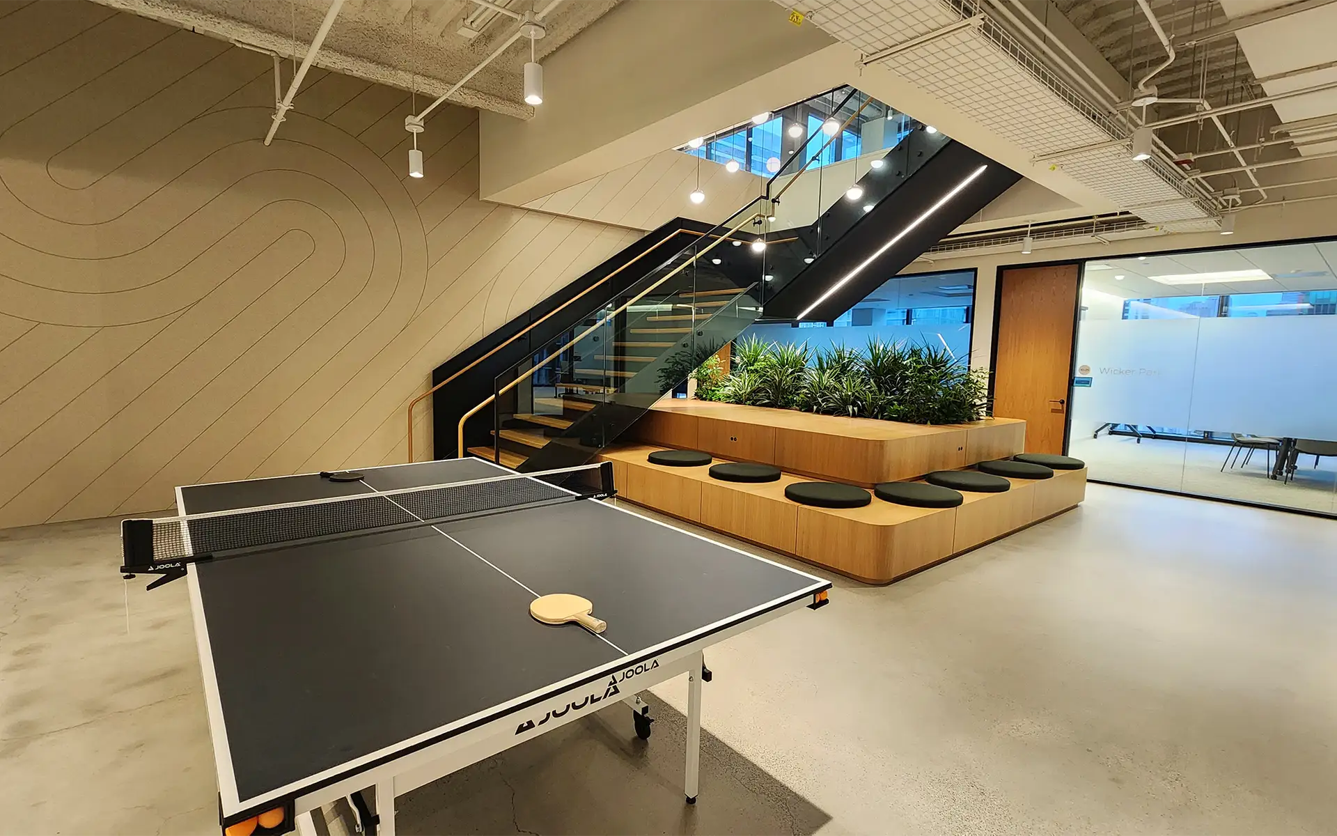 An open concept office space featuring beautiful, neutral acoustic wall panels next to a ping-pong table