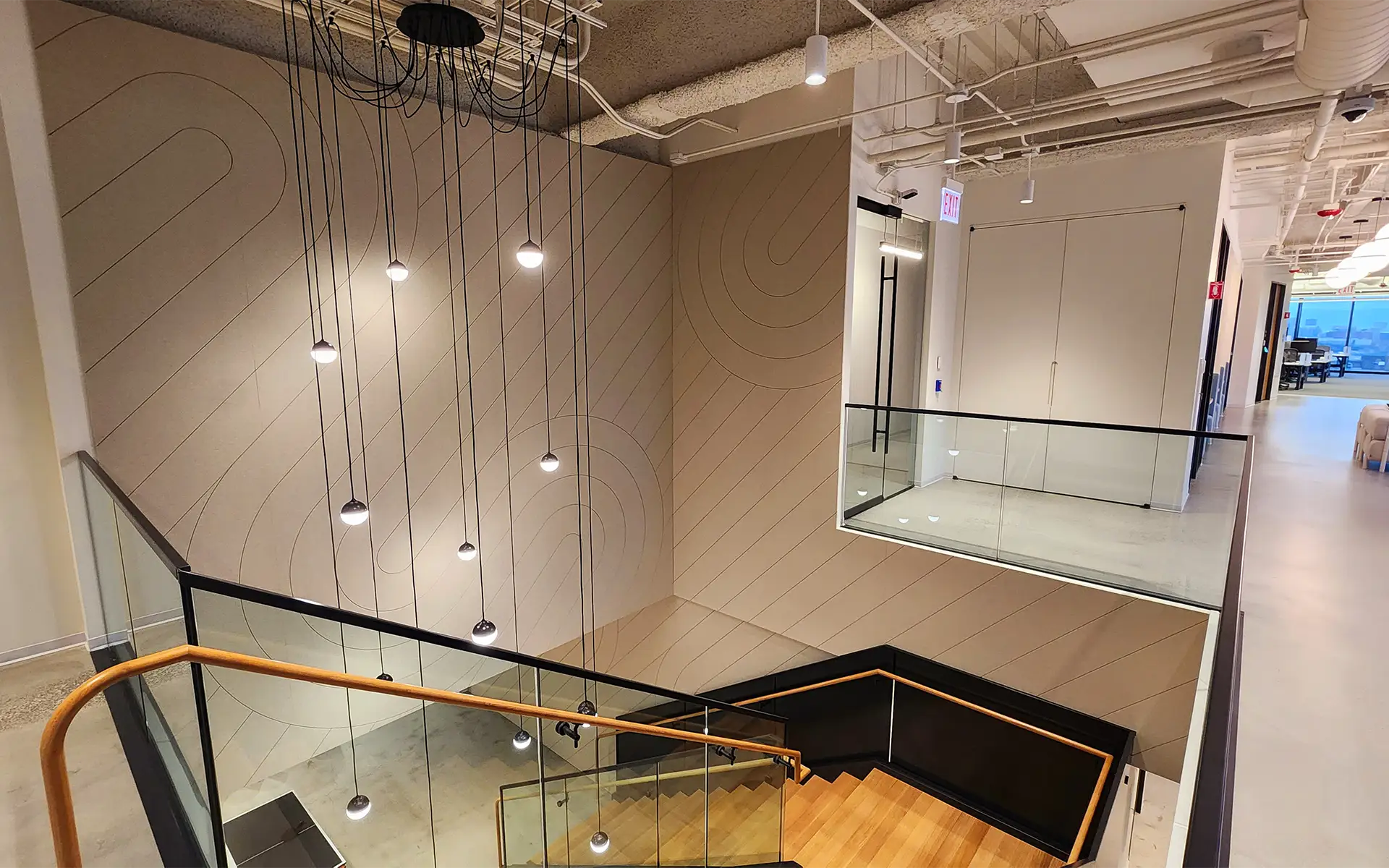 A modern office space featuring designer acoustic wall panels by the stairwell on the second story